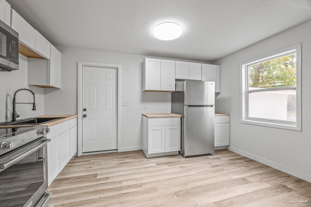 kitchen featuring white cabinetry, stainless steel appliances, light hardwood / wood-style floors, and sink