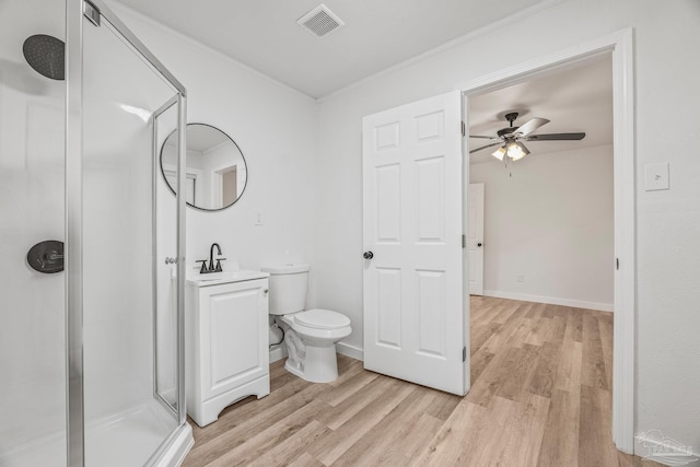 bathroom with toilet, a shower with shower door, crown molding, wood-type flooring, and vanity