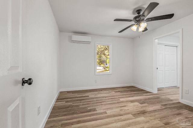 empty room featuring hardwood / wood-style floors, an AC wall unit, and ceiling fan