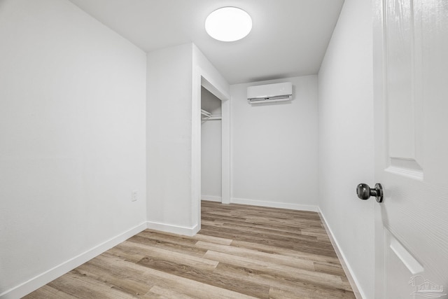 spacious closet with a wall unit AC and light hardwood / wood-style floors