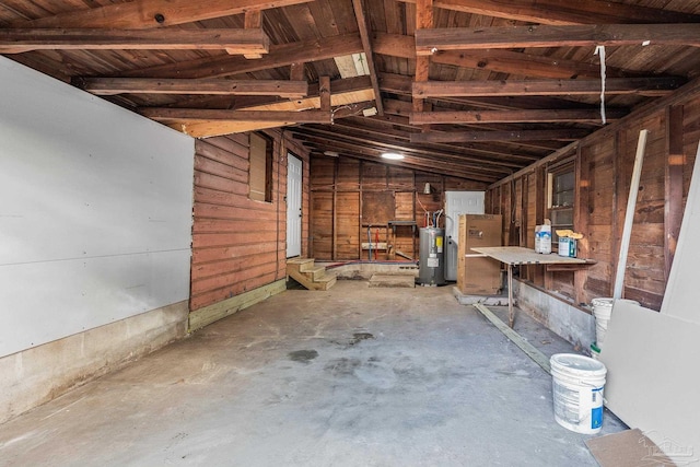 miscellaneous room featuring water heater, lofted ceiling, concrete floors, and wood walls