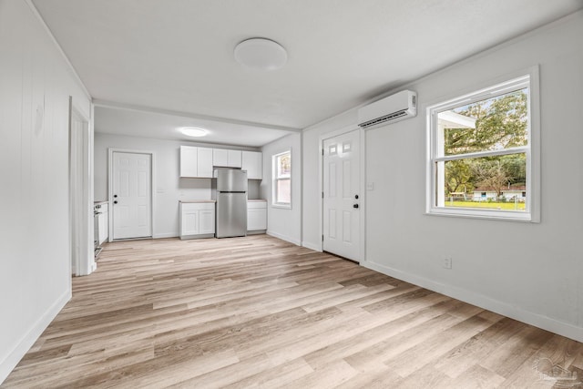 unfurnished living room with an AC wall unit and light wood-type flooring