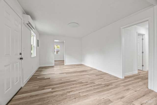 empty room with crown molding, a wall mounted AC, and light hardwood / wood-style flooring