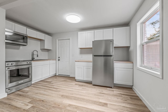 kitchen featuring white cabinetry, appliances with stainless steel finishes, sink, and a wealth of natural light