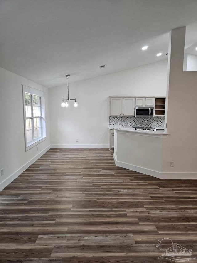 unfurnished living room featuring dark wood-type flooring and a chandelier