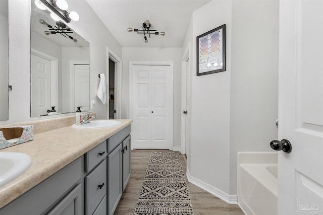6439 Dallas Ave, Pensacola, FL 32526 - bathroom featuring double vanity, a bath, wood finished floors, a sink, and baseboards