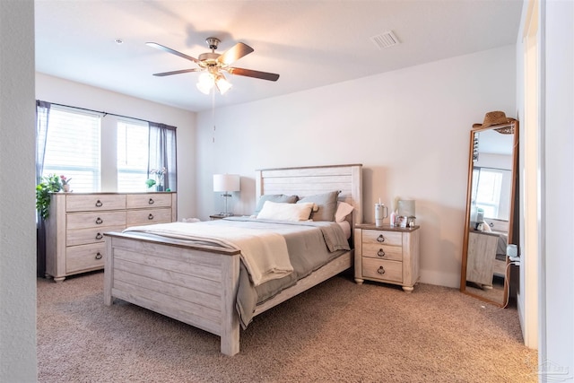 bedroom with light carpet, multiple windows, and ceiling fan