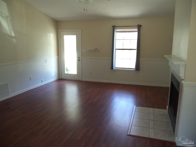 unfurnished living room featuring ceiling fan and dark hardwood / wood-style flooring