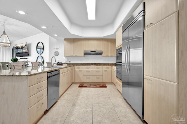 kitchen with a sink, stainless steel appliances, a peninsula, and light brown cabinets