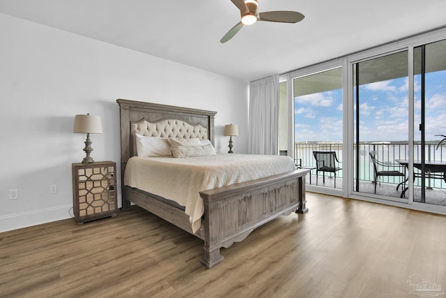 bedroom featuring access to exterior, baseboards, floor to ceiling windows, and wood finished floors