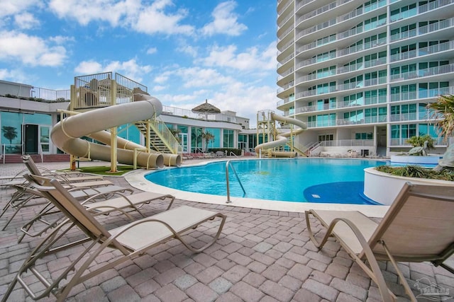 pool with a water slide and a patio