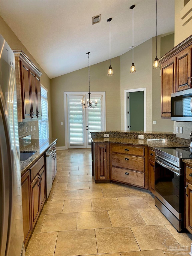 kitchen featuring lofted ceiling, dark stone counters, pendant lighting, an inviting chandelier, and appliances with stainless steel finishes