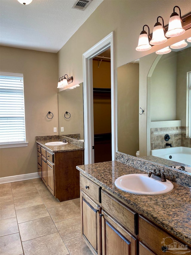 bathroom with vanity, a textured ceiling, tile patterned floors, and a tub to relax in