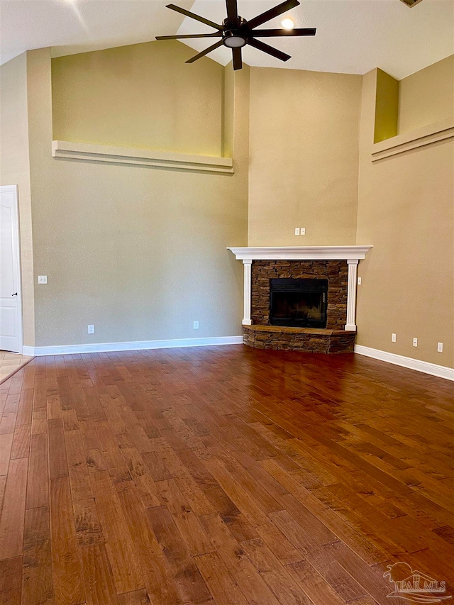 unfurnished living room featuring a stone fireplace, hardwood / wood-style flooring, high vaulted ceiling, and ceiling fan