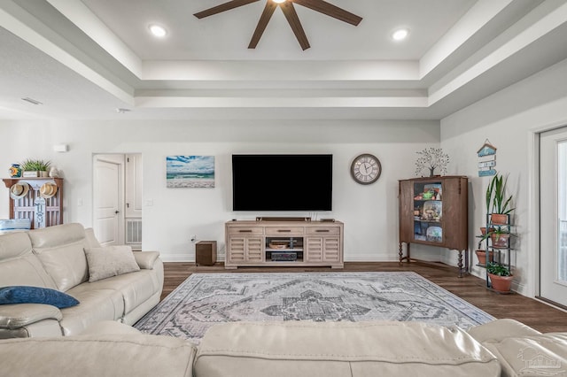 living room with ceiling fan, a raised ceiling, and wood finished floors