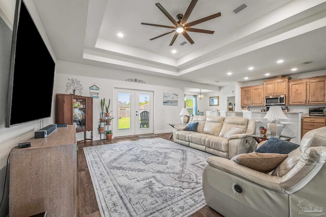 living area with a tray ceiling, a ceiling fan, visible vents, wood finished floors, and a toaster