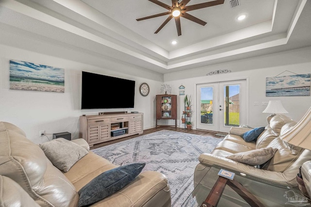 living room featuring french doors, a tray ceiling, visible vents, and ceiling fan