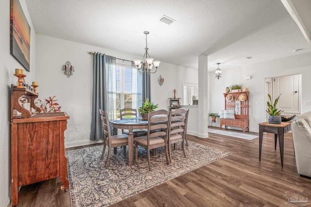 dining space with a chandelier, wood finished floors, baseboards, and visible vents