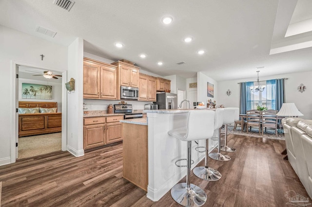 kitchen with a breakfast bar area, dark wood-style floors, visible vents, and stainless steel appliances