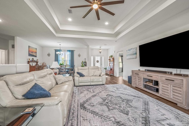 living room with recessed lighting, visible vents, a tray ceiling, ceiling fan with notable chandelier, and wood finished floors