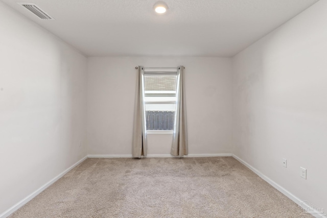 carpeted spare room with visible vents and baseboards