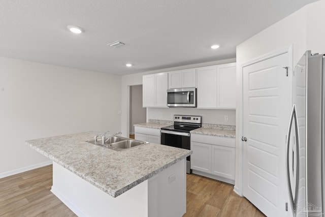 kitchen with visible vents, stainless steel appliances, light wood-type flooring, white cabinetry, and a sink