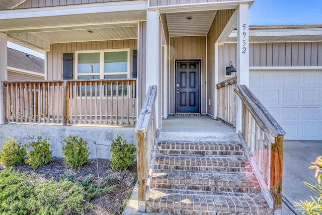 entrance to property with a garage, a porch, and board and batten siding