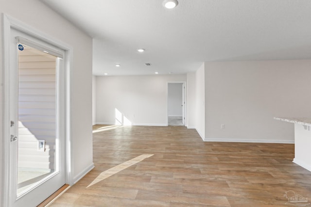 empty room with light wood-style floors, recessed lighting, visible vents, and baseboards