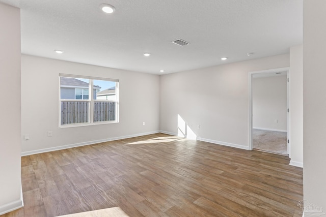 spare room featuring recessed lighting, visible vents, baseboards, and wood finished floors