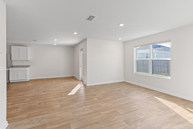 empty room with baseboards, light wood-style flooring, visible vents, and recessed lighting