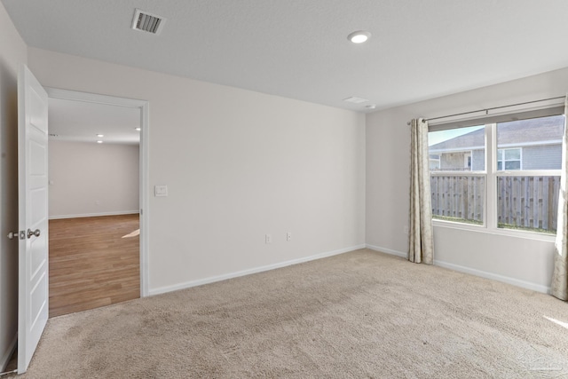 empty room with carpet, visible vents, and baseboards