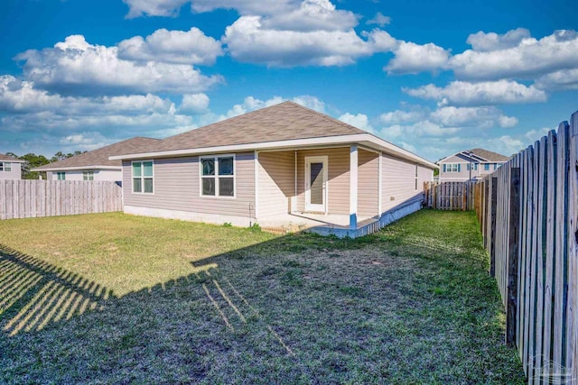 back of property with a yard, a shingled roof, and a fenced backyard