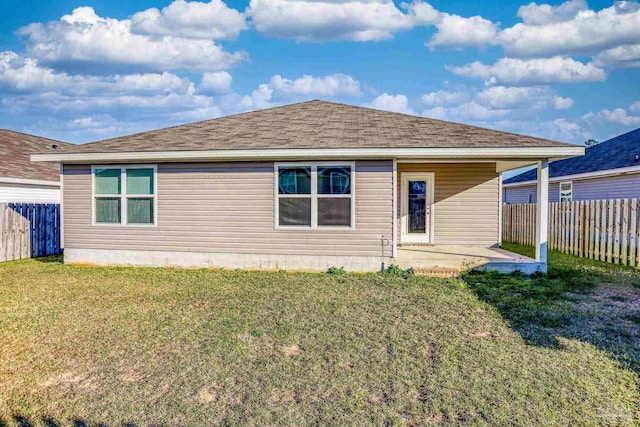 back of property with roof with shingles, a fenced backyard, a yard, and a patio