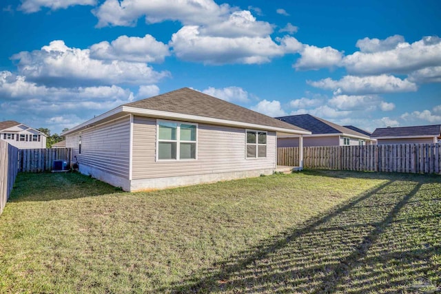 back of house with a fenced backyard, roof with shingles, central AC, and a yard