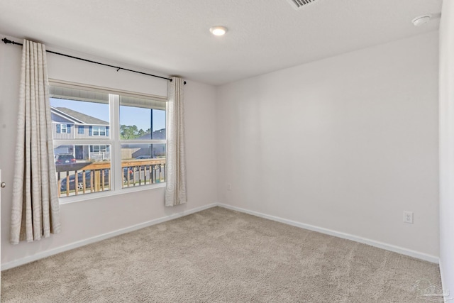 empty room featuring carpet, baseboards, and a textured ceiling