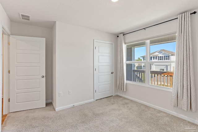 unfurnished bedroom with carpet floors, visible vents, and baseboards