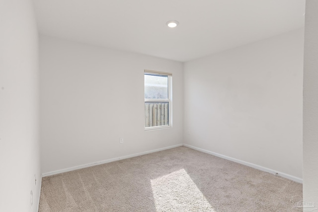 carpeted empty room featuring baseboards