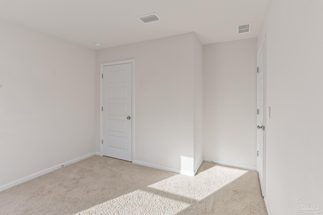 spare room with carpet, visible vents, and baseboards