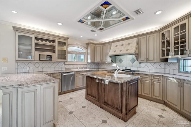 kitchen featuring premium range hood, light stone counters, a center island with sink, stainless steel dishwasher, and decorative backsplash