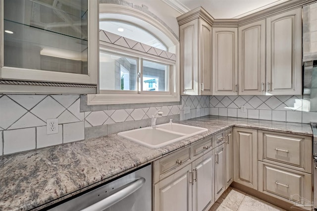 kitchen with dishwasher, light stone countertops, sink, and backsplash