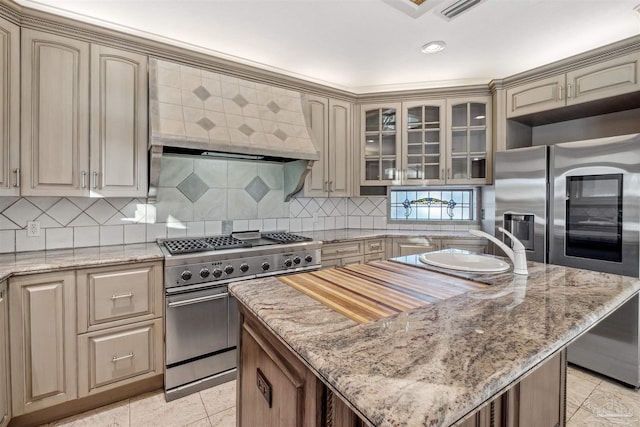 kitchen with light stone counters, decorative backsplash, stainless steel appliances, and a kitchen island