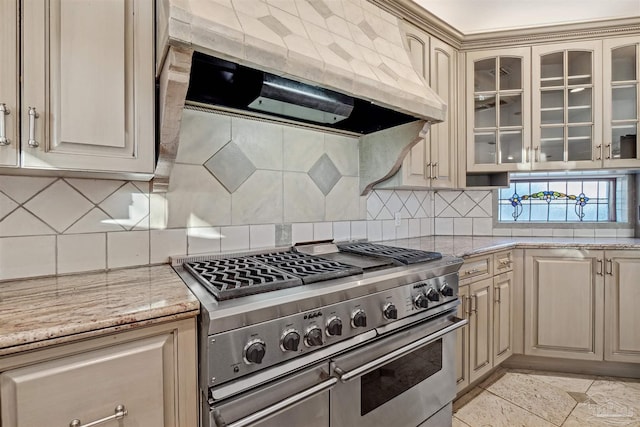 kitchen featuring premium range hood, decorative backsplash, light stone counters, and range with two ovens