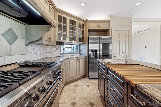 kitchen featuring sink, crown molding, stainless steel appliances, light stone countertops, and decorative backsplash