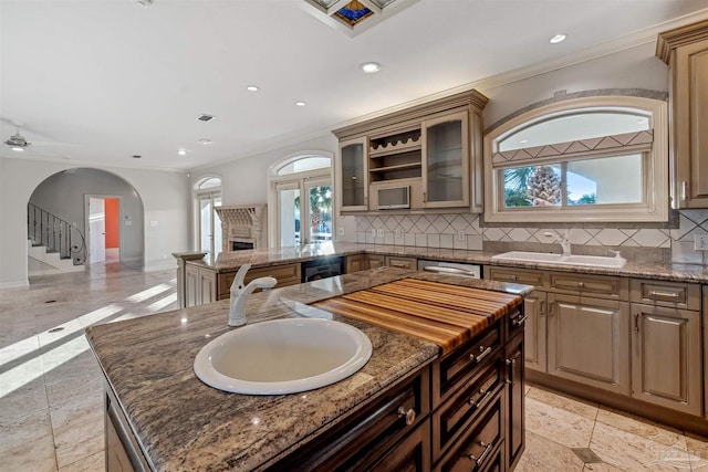 kitchen with sink, decorative backsplash, a center island, and dark stone counters