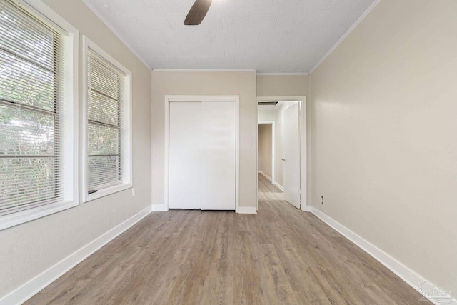 unfurnished bedroom with crown molding, light hardwood / wood-style flooring, a closet, and ceiling fan