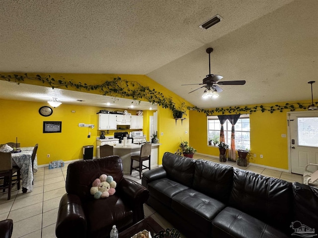 living room with ceiling fan, light tile patterned floors, a textured ceiling, and vaulted ceiling