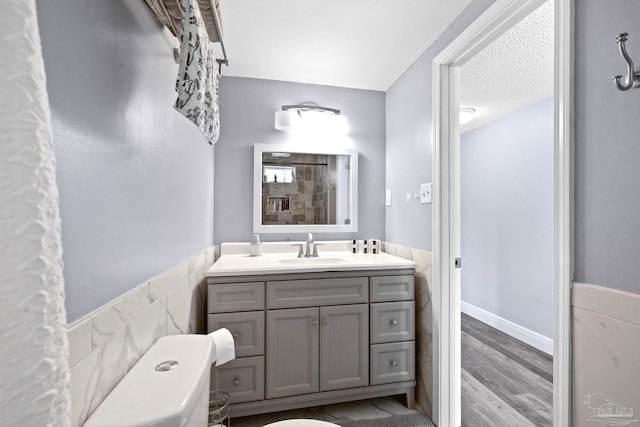 bathroom featuring hardwood / wood-style floors, vanity, toilet, and tile walls