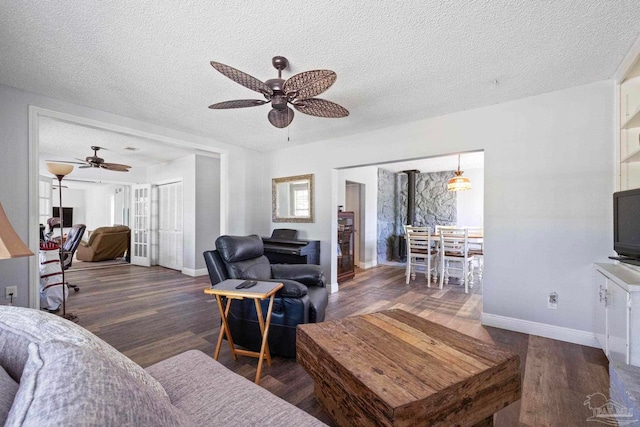 living room with a textured ceiling, dark hardwood / wood-style floors, and ceiling fan