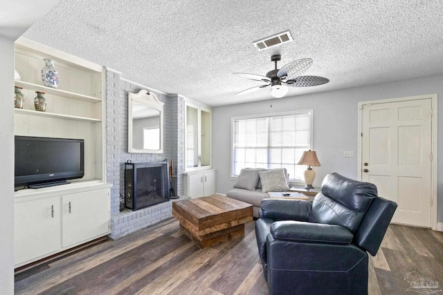 living room with a fireplace, ceiling fan, dark hardwood / wood-style flooring, and a textured ceiling