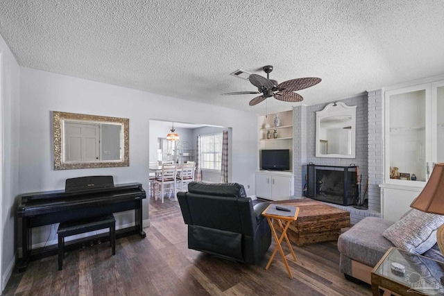 living room featuring dark hardwood / wood-style floors, ceiling fan, a textured ceiling, and a fireplace